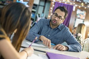 Kal Penn working with a student